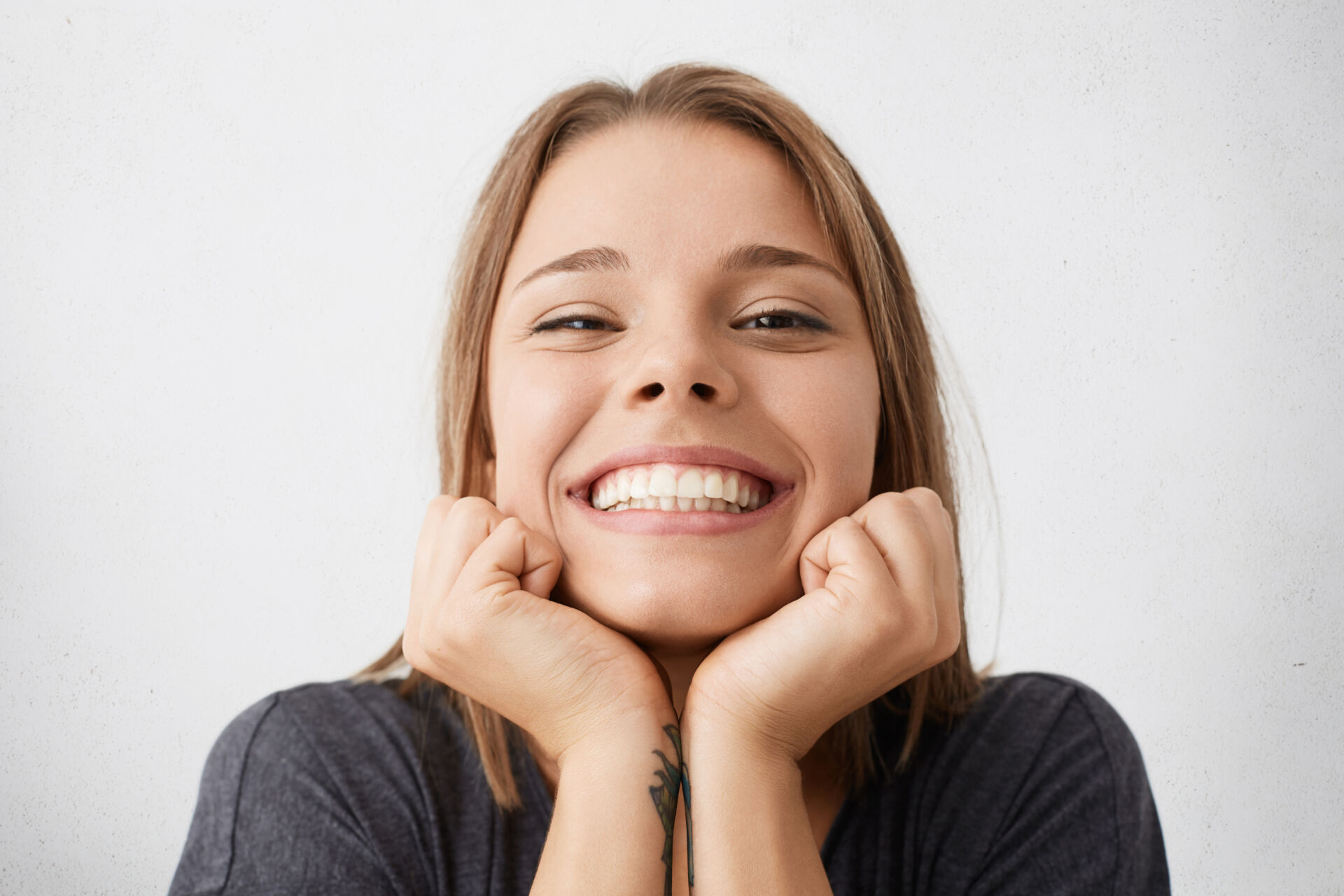 Close up indoor portrait happy excited young female celebrating success promotion work looking with broad cheerful smile holding hands her face feeling joy happiness